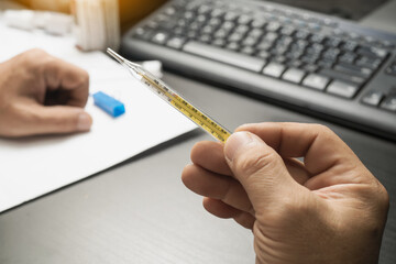 men hand holding clinical thermometer on working desk,After using the clinical thermometer and worry about coronavirus spread