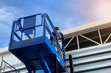 Look up view and flare. Mechanic standing on the scissor forklift. For the installation of...