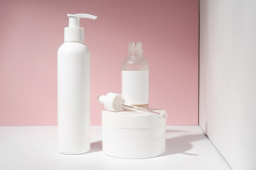 Three jars of cosmetics stand on a white and pink background.
