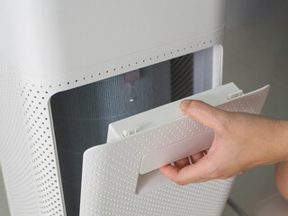 A woman's hand is changing the air purifier filter in a dusty house to replace a new one, PM 2.5.