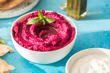 Humus Bowl. Red beetroot hummus with fresh vegetables, olive oil on table
