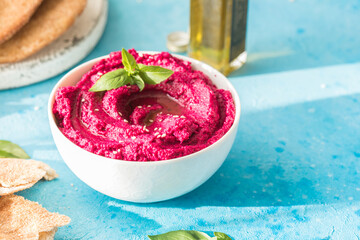 Humus Bowl. Red beetroot hummus with fresh vegetables, olive oil on table - obrazy, fototapety, plakaty