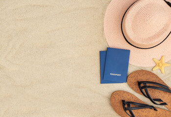 Fototapeta na wymiar Beach hat with flip flops and passports on sand. Space for text. Vacation travel.