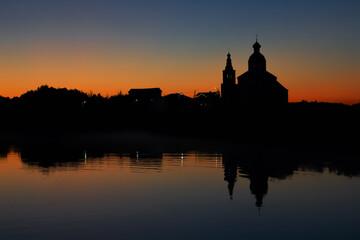 Fototapeta na wymiar Silhouette of the Church of Elijah the Prophet at sunset in Suzdal. Nature background sunset on the river.