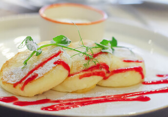 Cheesecakes with sour cream. Yummy dessert. Cheesecakes on a white plate. Traditional Russian dish. Close-up.