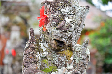 Statue in Taman Ayun temple with red flower on the ear