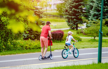 Obraz premium Father and daughter ride bicycles in the city park