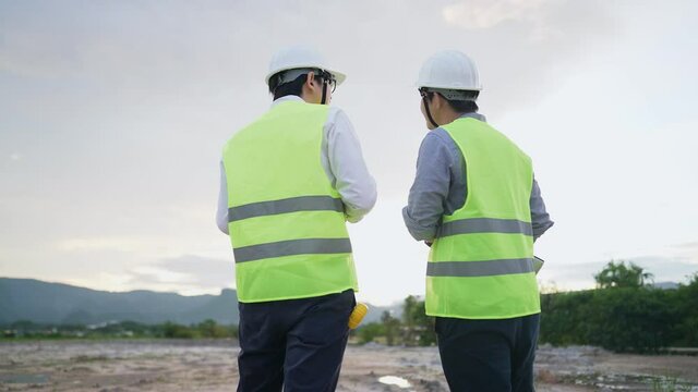 Diverse worker of specialists using technology wireless devices discussing plan details on construction site, property building on empty land project with civil engineer, architectural, teamwork conce