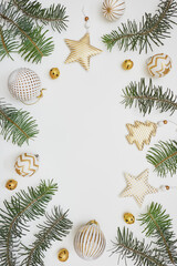 Christmas frame made of fir tree branches and golden decorations on white background