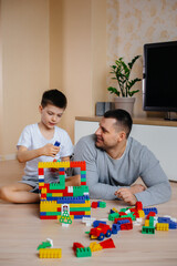 Fototapeta premium A little boy together with his father is played by a constructor and builds a house. Construction of a family home.