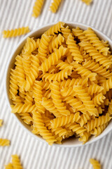 Uncooked Yellow Organic Rotini Pasta, top view. Flat lay, overhead, from above. Closeup.