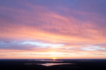Fototapeta premium Aerial view of a sunset sky background. Aerial Dramatic gold sunset sky with evening sky clouds over the lake. Stunning sky clouds in the sunset. Sky landscape. Aerial photography.