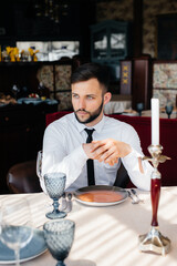 A young bearded male businessman is sitting at a table in a fine restaurant and waiting for his order. Customer service in the catering.