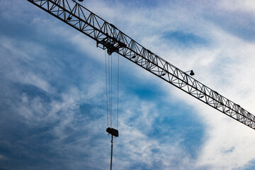 Tower crane close-up on a background of blue sky. Modern housing construction. Industrial engineering. Construction of mortgage housing.