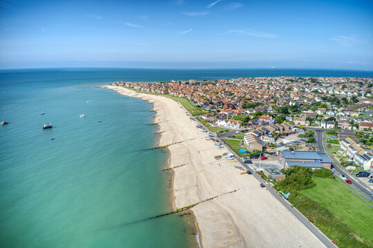 East Beach in Selsey West Sussex with small boats lined up on the wide shingle beach. Aerial photo.
