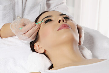 Obraz na płótnie Canvas Young woman undergoing eyelash lamination and tinting in salon