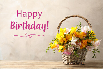 Happy Birthday! Beautiful freesia flowers in wicker basket on table