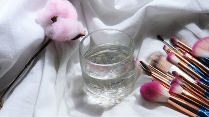 water on white background with makeup brushes