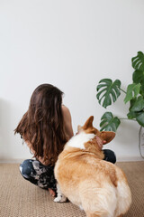 Woman doing yoga and meditating on jute rug with corgi dog