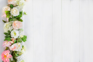 Floral decoration of soft pink and yellowish flowers on a white wooden background. Invitation, postcard, greeting concept