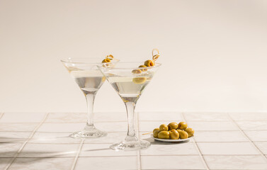 Martini cocktail with olives on the tiled table. An alcoholic classic drink with ice in an elegant...