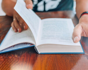 Close-up of a man sitting at a wooden table and reading a book