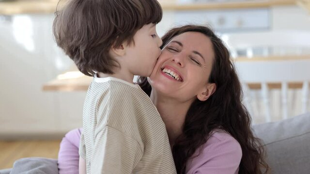 Small caucasian boy of five kissing joyful mother. Close up portrait of overjoyed happy mom and cute preschool son cuddling together at home. Young family bonding. Caring parent together with child