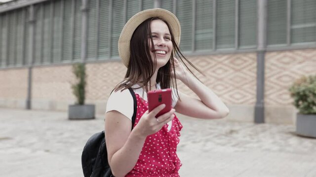Happy smiling young adult hipster tourist woman using mobile phone while enjoying sightseeing walking on urban city street in Barcelona, Spain, Europe. High quality 4k footage