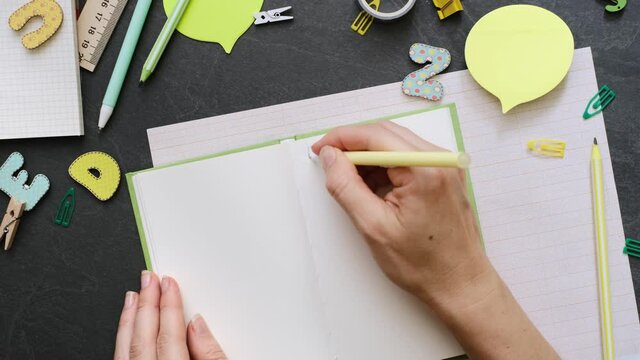 Back to school concept. Person prepares a plan for studying with school supplies on the black background. Top view with copy space. Working table for creative job or planning