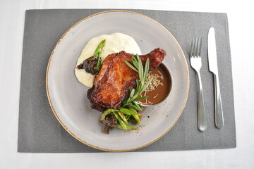 Texas grilled chicken leg confit with vegetables, mash potato and chef brown sauce in white background western main course menu