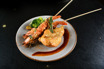 mixed grilled seafood skewer platter big tiger pawn with deep fried chicken and vegetables salad in black background western menu