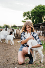 A young pretty girl poses on a ranch with goats and other animals. Agriculture, livestock breeding