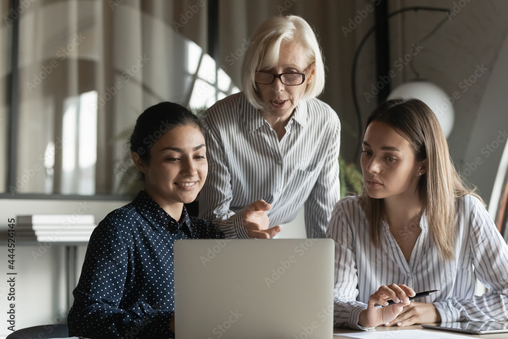 Canvas Prints corporate teacher showing and explaining work data to student girls, pointing at laptop screen, spea