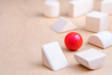 A wooden red ball in a group of other geometric wood toys as business strategy, position in the...