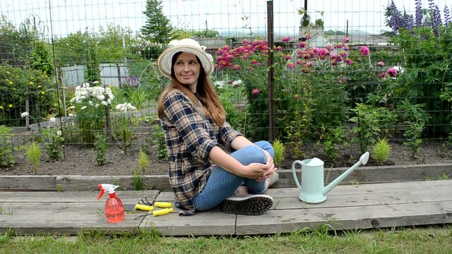 caucasian woman in garden with flowrs relaxing after working