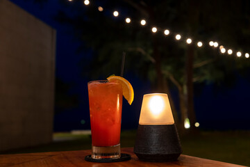 A glass of cocktail from the beach bar in hotel with a beautiful night view in the background