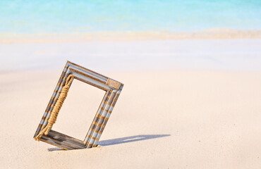 Fototapeta premium Wooden Photo frame on the tropical sea sand and the beach background with copy space