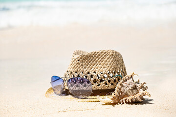 Straw summer hat, sea shell and sunglasses on seaside shore, summer tropical holiday