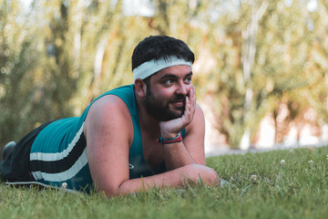 a fat boy lying down resting after sports in the open air.
will, determination.