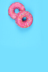 Pink donuts with colored noodles.
Blue background, copy space.