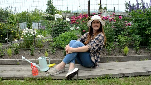 caucasian woman in garden with flowrs relaxing after working