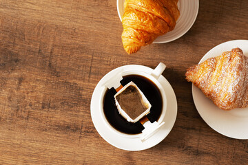 Cup of coffee with drip filter and croissant