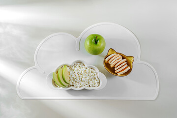 Children's Breakfast. Plate in the shape of a cloud with cottage cheese, berrys, apple and snacks. Food idea for kids.