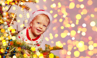 Cute toddler boy looking behind of Christmas tree