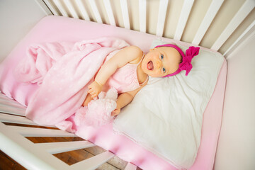 Fototapeta na wymiar Baby girl lay in crib bed laugh and look up