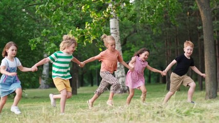 Group of five happy kids running on grass in green park holding hands and screaming with excitement. Children celebrating friendship and togetherness, side view slow motion shot - Powered by Adobe