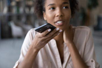 Close up cropped of African American woman recording audio message on smartphone, holding modern device, positive young female chatting online by speakerphone, activating digital voice assistant