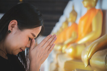 Asian woman pays homage to the Buddha statue with respect and faith - obrazy, fototapety, plakaty
