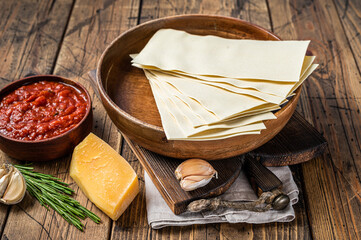 Fototapeta na wymiar Set of ingredients for cooking lasagna close-up of Tomato sauce, pasta, cheese. wooden background. Top view