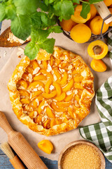 French Galette or a pie with apricots and almonds on on a blue culinary background top view. Summer homemade sweet pastries	